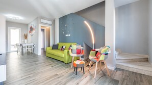 Una sala de estar moderna con un sofá verde, una zona de comedor y una escalera.