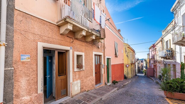 Una estrecha calle adoquinada bordeada de edificios coloridos, cada uno con detalles arquitectónicos y balcones únicos.