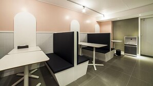 A modern waiting area with white and black seating, a small table, and a trash bin. - Gunsan Hotel Box (Gunsan)