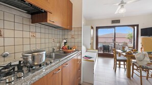 A kitchen with wooden cabinets, a gas stove, and a dining area with a table and chairs.