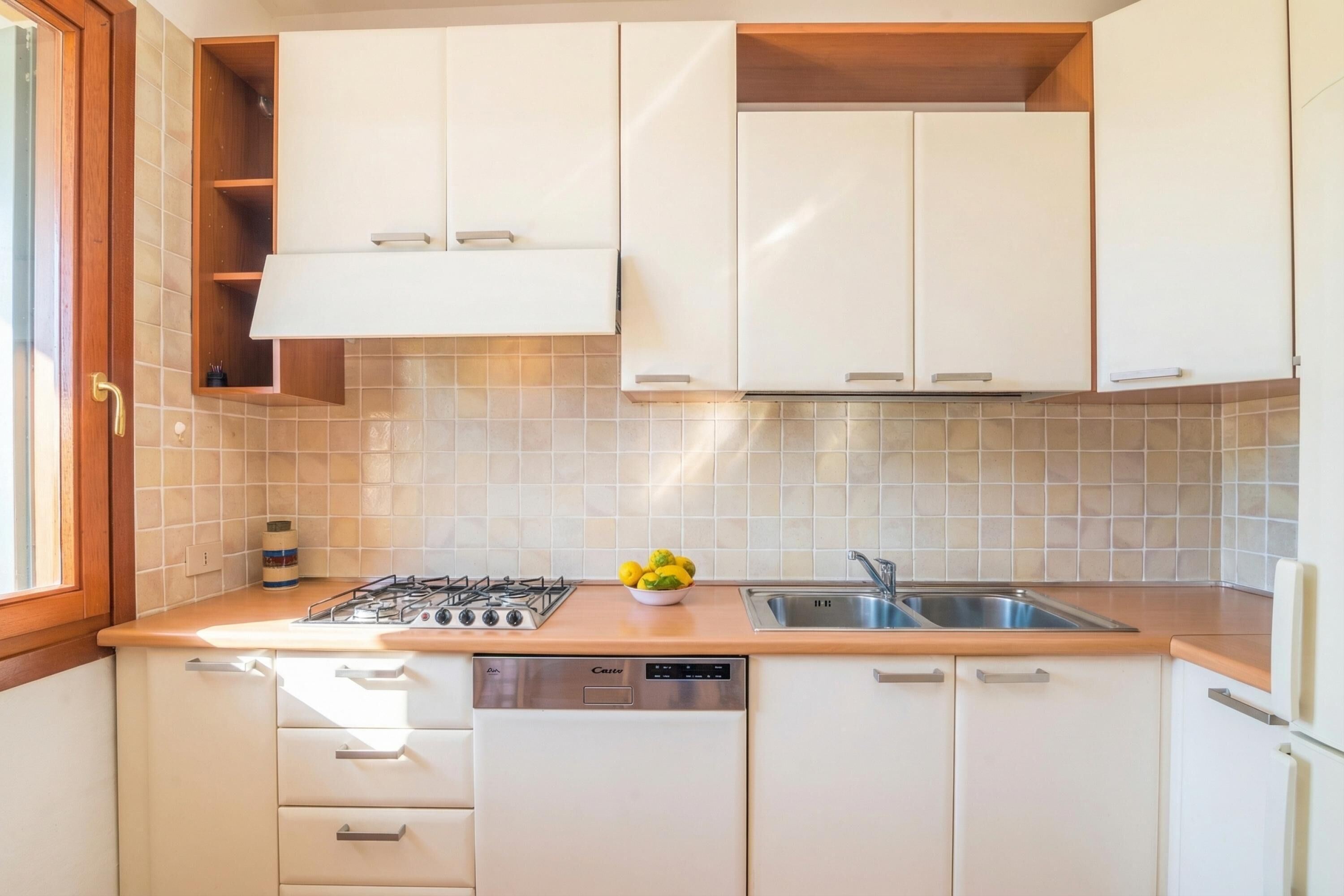 A kitchen with white cabinets, a dishwasher, a stove, and a sink.