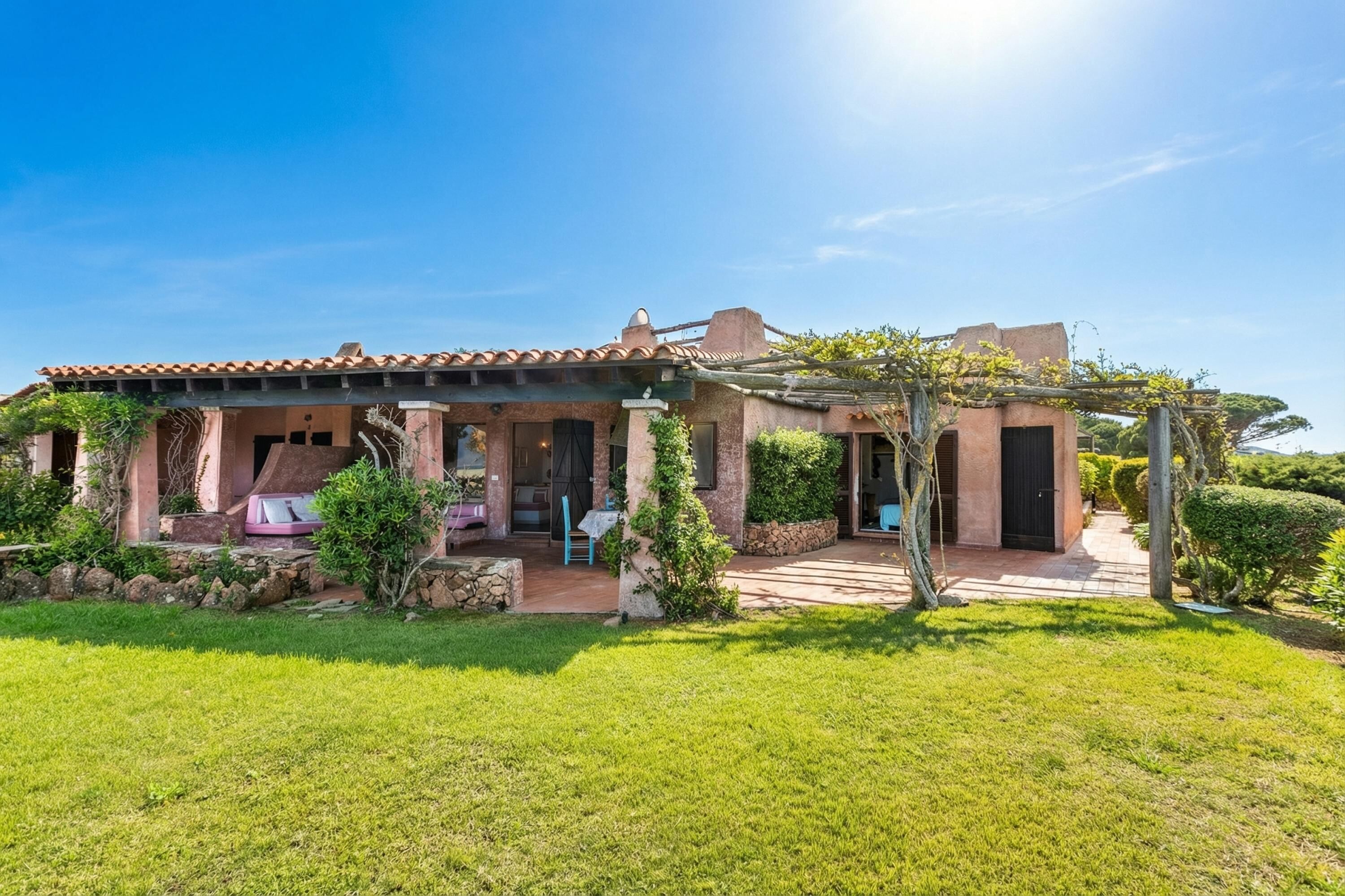 Una casa con un patio, un porche cubierto y un césped bien cuidado.