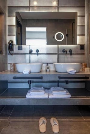Un bagno moderno con due lavabi, uno specchio grande e un porta asciugamani.