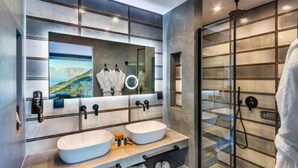 Un baño moderno con dos lavamanos, un espejo grande y cabina de ducha con mampara de vidrio.