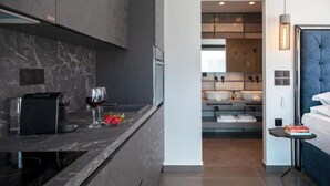 Una cocina moderna con encimera de mármol, una cafetera y una copa de vino.
