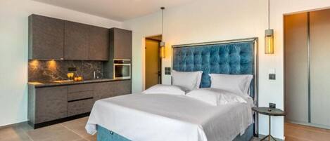 Una habitación de hotel moderna con una cama grande, cocina integrada y baño independiente.