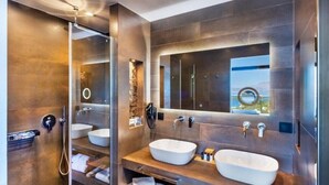 Ein modernes Badezimmer mit zwei Waschbecken, einer Duschkabine aus Glas und einem großen Spiegel.