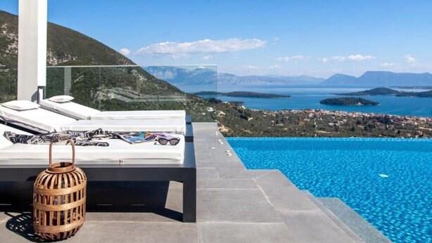 Ein moderner Poolbereich im Freien mit freiem Blick auf das Meer und die Berge.