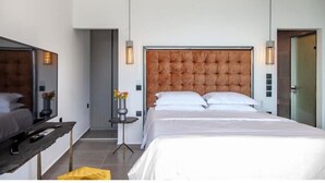 Ein modernes Hotelzimmer mit einem großen Bett, einem Nachttisch, einem Spiegel und einem kleinen Beistelltisch mit Blumen in einer Vase.