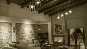 A modern living room with a stone wall, a sofa, a flat-screen TV, and a fireplace.