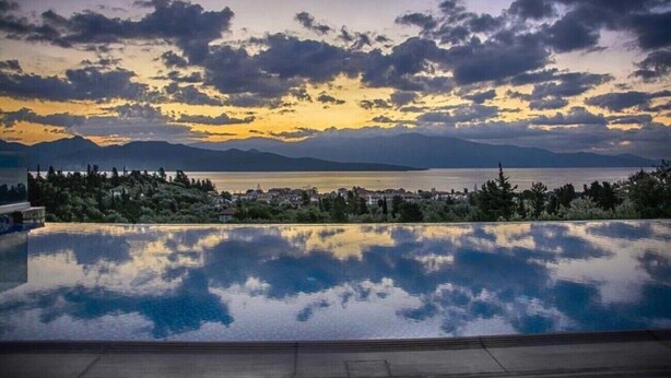 A swimming pool with a view of the sea and mountains.