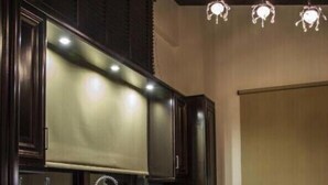 A kitchen with dark wood cabinets, a stainless steel sink, and pendant lighting.