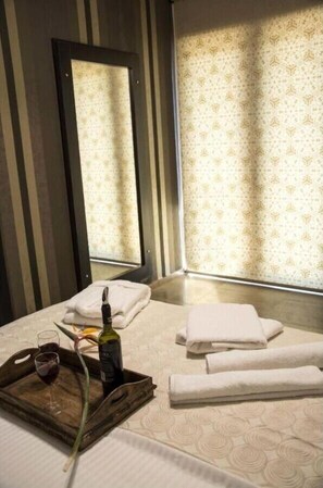 A hotel room with a bed, a tray with a bottle and glass, towels, and a window with patterned curtains. - "Villa Kastro" with Sea View, Private Pool, Garden and Balcony (Lefkada)
