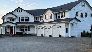 A large, two-story house with a covered driveway and multiple garage doors. - Beautiful Valley Farm House, With View (Puyallup)