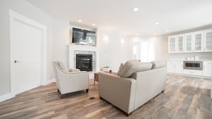 A spacious living room with a fireplace, a sofa, and a television mounted above it. - Beautiful Valley Farm House, With View (Puyallup)