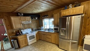 A kitchen with wooden cabinets, a stainless steel refrigerator, a stove, and a microwave.
