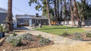 A residential property with a stone patio, a lawn, and a wooden fence. - Chic Boho Getaway Near Downtown Visalia (Visalia)