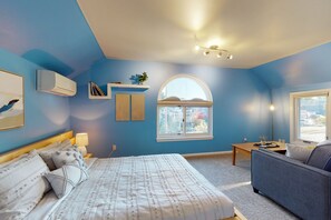 Een slaapkamer met een bed, een sofa, een raam en een wandairconditioner.