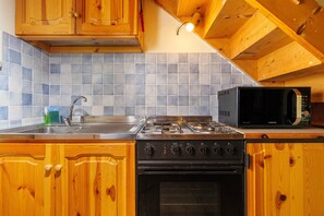 A kitchen with wooden cabinets, a stainless steel sink, a gas stove, and a microwave.