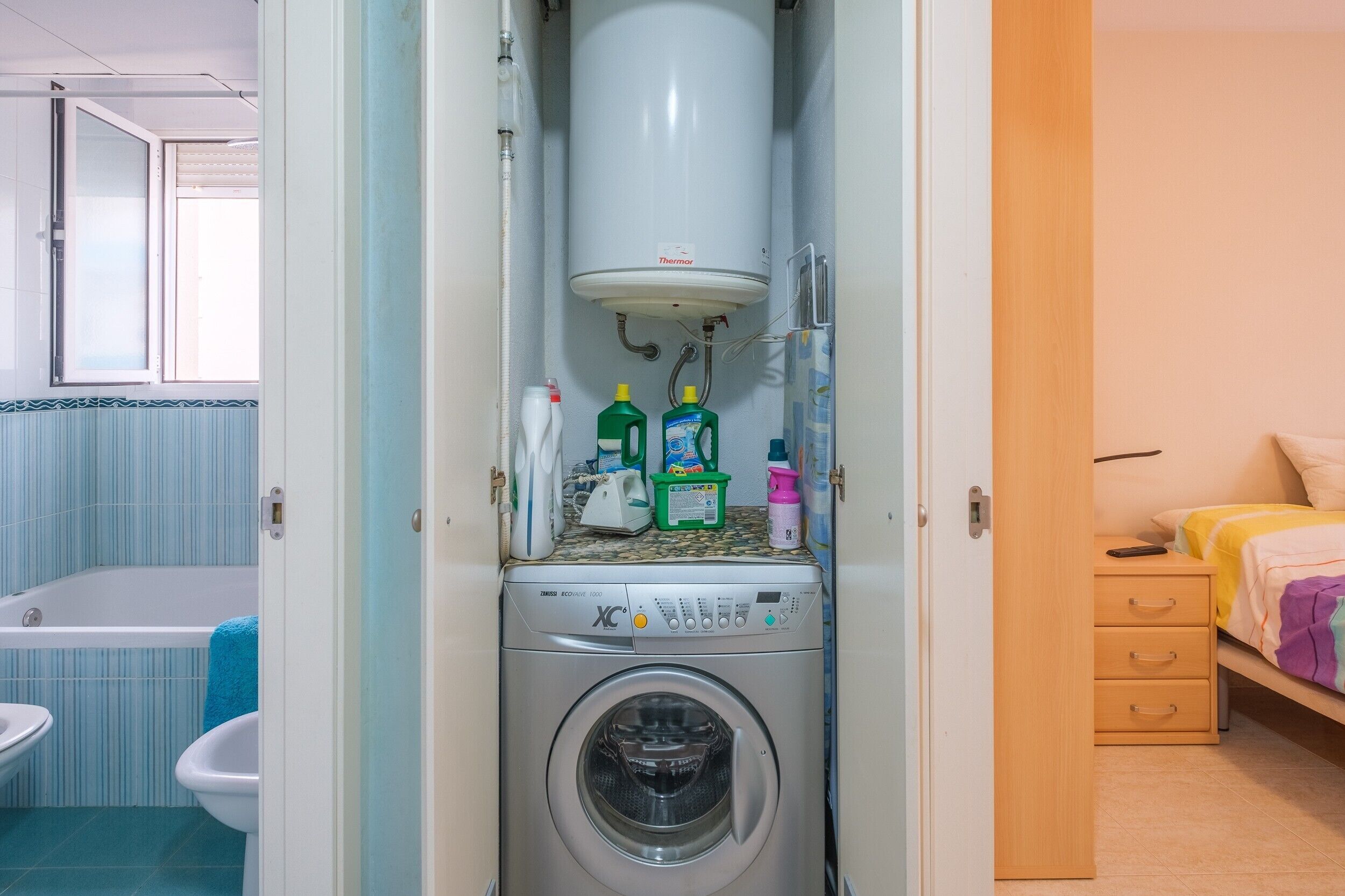 Habitación compacta con lavadora, bañera y cama.