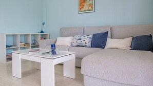 A living room with a sofa, a coffee table, a bookshelf, and a painting on the wall. - Apartment "Merida" with Shared Pool, Terrace and Wi-Fi (ALCANAR)
