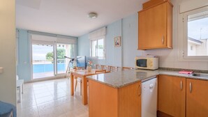 A kitchen with wooden cabinets, a microwave, and a dining area with chairs and a table. - Apartment "Merida" with Shared Pool, Terrace and Wi-Fi (ALCANAR)