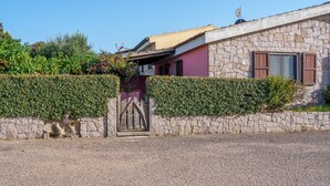 Ein Steinhaus mit einem verschlossenen Eingang, einer Steinmauer und einer Hecke.
