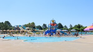 A swimming pool area with a water slide, lounge chairs, and umbrellas. - Holiday Apartment "Mobile-home Alain" with Garden & Terrace (Saint-Julien-en-Born)