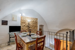 Ein Essbereich mit Steinwand, einem Tisch mit Stühlen, einem Fernseher auf einer Glastruhe und einer Treppe mit Geländer.