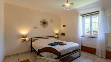 Un dormitorio con cama, lámparas de noche, una ventana con cortinas, cabecera de madera y decoración en la pared.