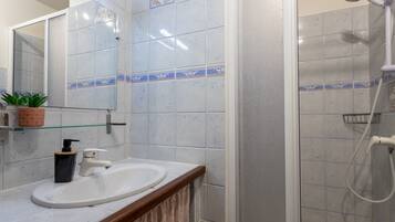 Un bagno con lavandino, specchio, doccia e pareti piastrellate.