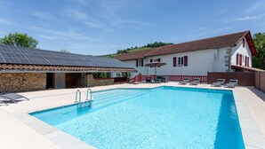 A swimming pool with a stone wall, a red-roofed building, and a clear sky. - Holiday Home "Maison Elixondoa" with Mountain View, Wi-Fi (Pagolle)
