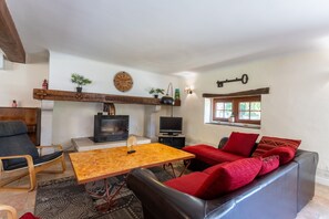 Uma sala de estar com lareira, televisão e área de estar.
