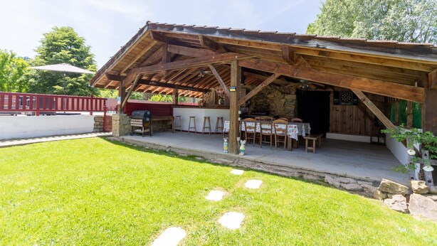 A rustic outdoor dining area with a wooden pergola, stone steps, and a stone wall. - Holiday Home "Maison Elixondoa" with Mountain View, Wi-Fi (Pagolle)