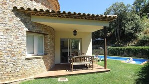 Un edificio de piedra con un patio, piscina y jardín.