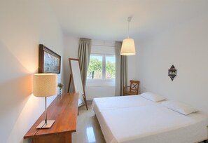 A bedroom with a bed, a desk with a lamp, a chair, a window with curtains, and a wall-mounted light fixture. - Villa "with Pool Ac and Sea View" with Pool, Garden & Wi-Fi (Begur)