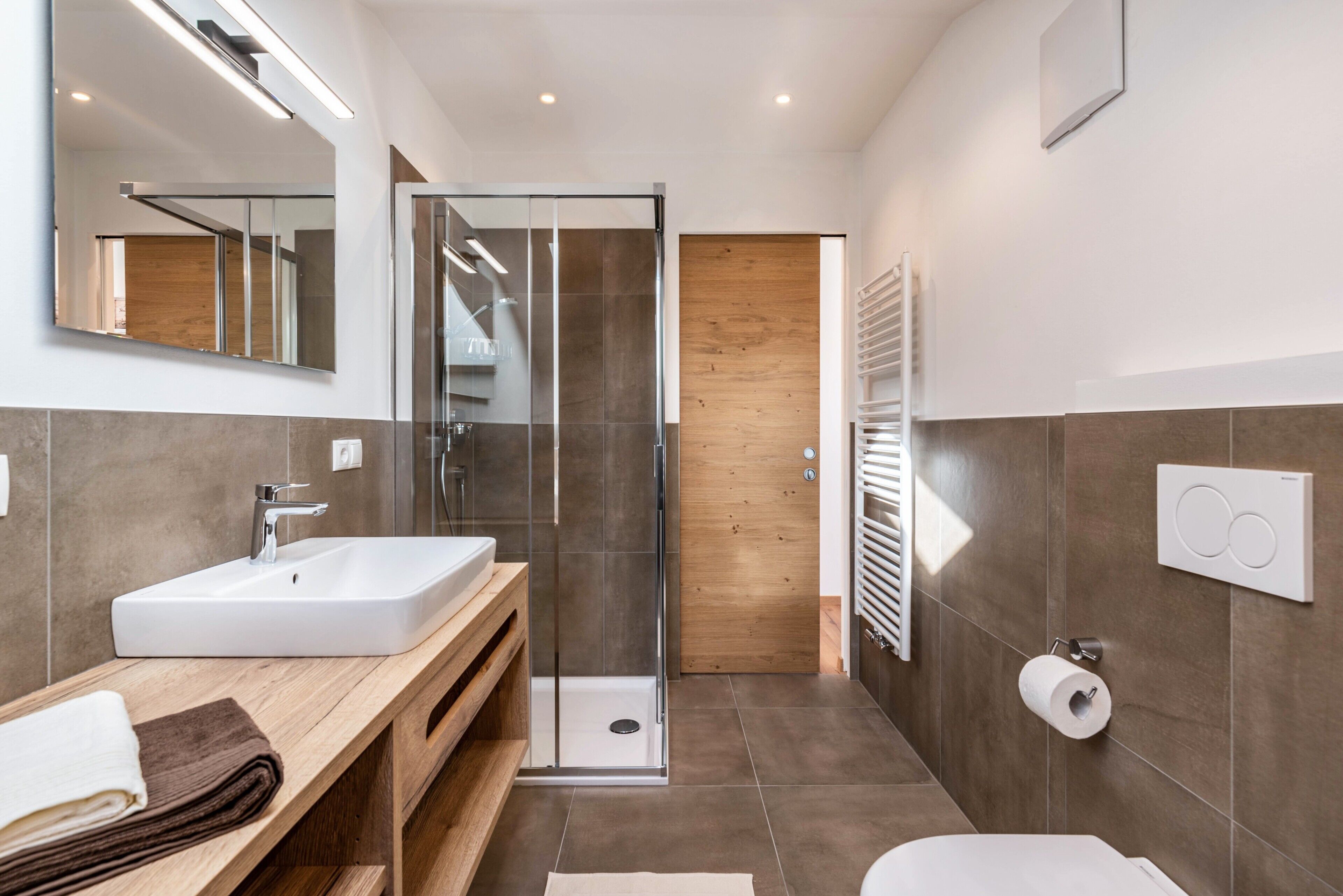 Ein modernes Badezimmer mit Duschkabine aus Glas, einem weißen Waschbecken und einer Toilette.
