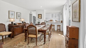Un espace repas comprenant une longue table en bois, des chaises et un tapis à motifs.