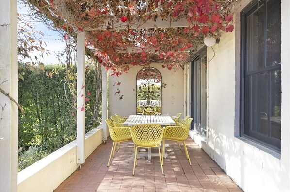 Relax in a serene outdoor space surrounded by lush greenery and enjoy meals at a table with comfortable seating.
