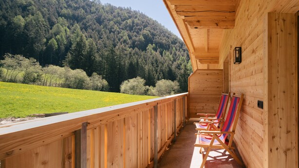 Una cabaña de madera con balcón que da a una ladera boscosa.