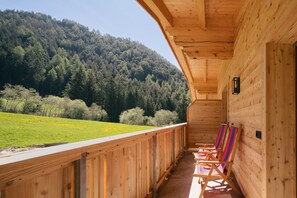 Une cabane en bois dotée d’un balcon donnant sur une colline boisée.