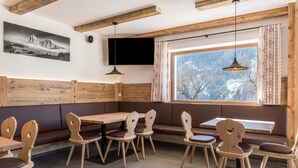 Un restaurante con mobiliario de madera, un amplio ventanal con vistas y un televisor montado.