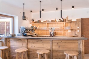Uma área de bar com estantes de madeira, banquetes e uma máquina de café.