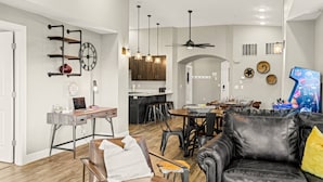 Ein geräumiges Wohnzimmer mit einer Ledersofa, einem Essbereich mit Tisch und Stühlen, einer Küche mit Holzausstattung und einem Deckenventilator.