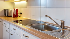 A modern kitchen with a stainless steel sink, a built-in induction cooktop, and white cabinets.