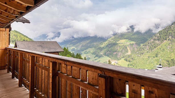 A wooden balcony with a view of a mountainous landscape.