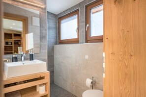 Un baño moderno con un lavamanos grande, espejo y tocador de madera.