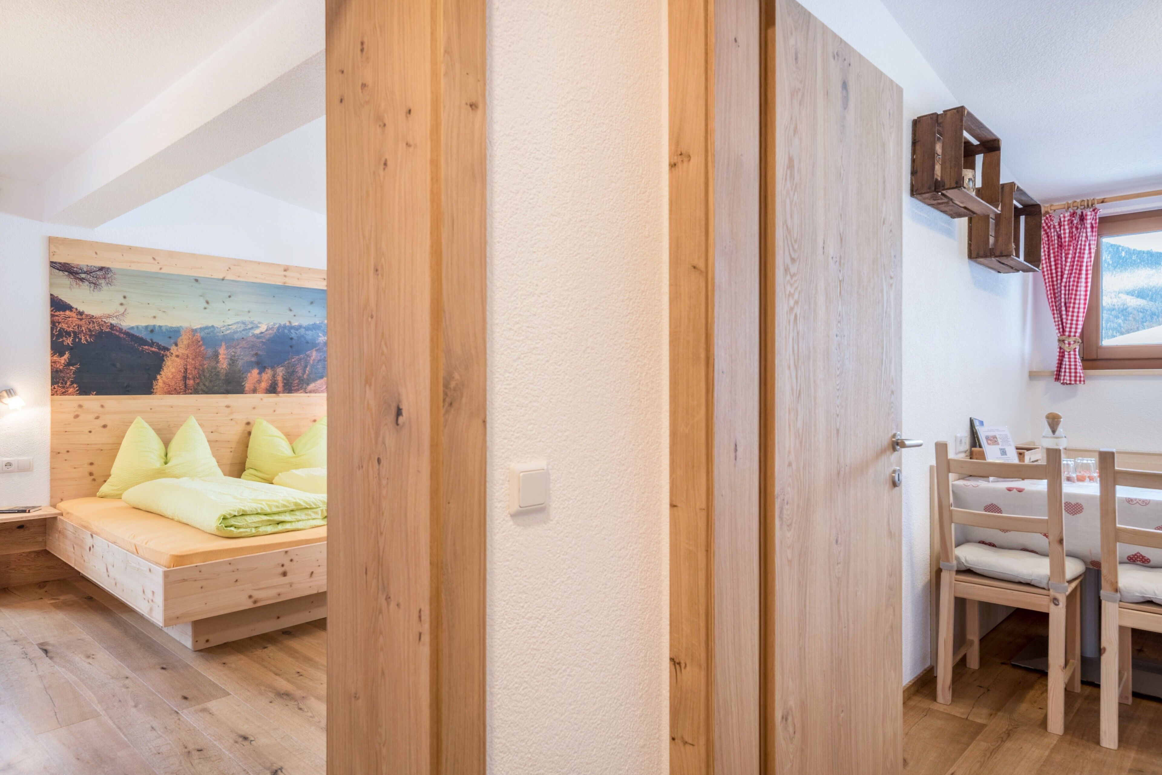 Un lit en bois avec des oreillers, une petite table de chevet et un tableau représentant un paysage de montagne.