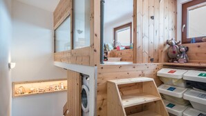 Habitación con paredes de madera, lavadora y contenedores de almacenamiento.