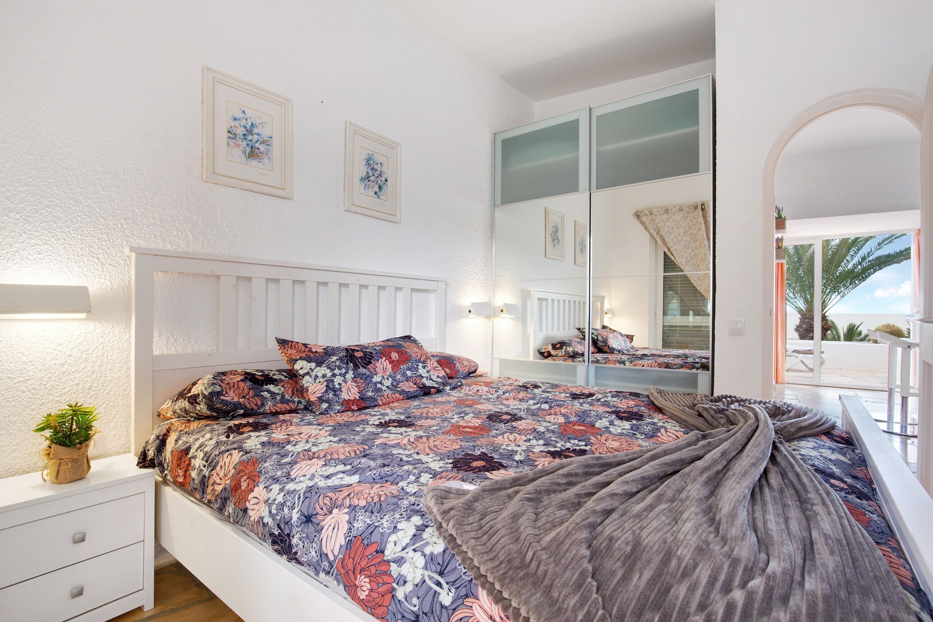 A bedroom with a bed, bedside table, and a mirror.